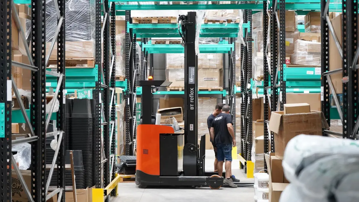 Entrepôt logistique avec rayonnages, cartons et chariot de manutention