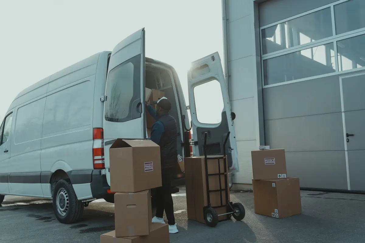 Cartons déchargés d’un utilitaire devant la porte d’un entrepôt